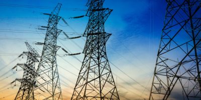 Sun setting behind the silhouette of electricity pylons